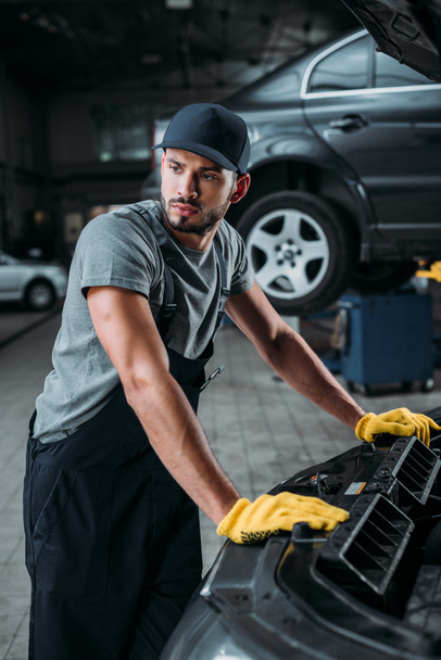 arbeider in overalls repareren auto in mechanische winkel - Foto, afbeelding