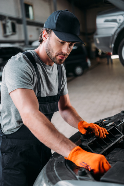 professional manual worker repairing car in mechanic shop - Fotoğraf, Görsel