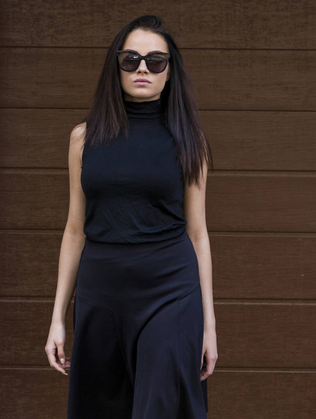 Beautiful woman in sunglasses posing on urban background - 写真・画像