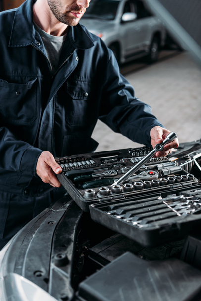 Ausgeschnittene Ansicht eines Mechanikers mit Werkzeugkoffer in der Autowerkstatt - Foto, Bild