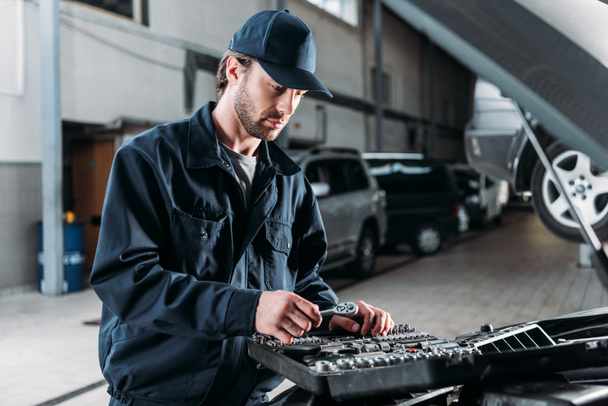 Mechaniker mit Werkzeugkoffer in der Autowerkstatt - Foto, Bild
