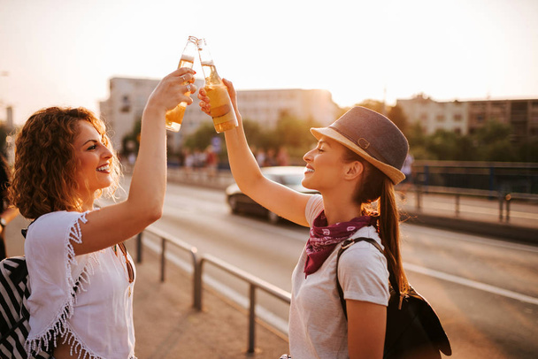 Two beautiful hipster women toasting in the city street in the summer. - Foto, Imagem
