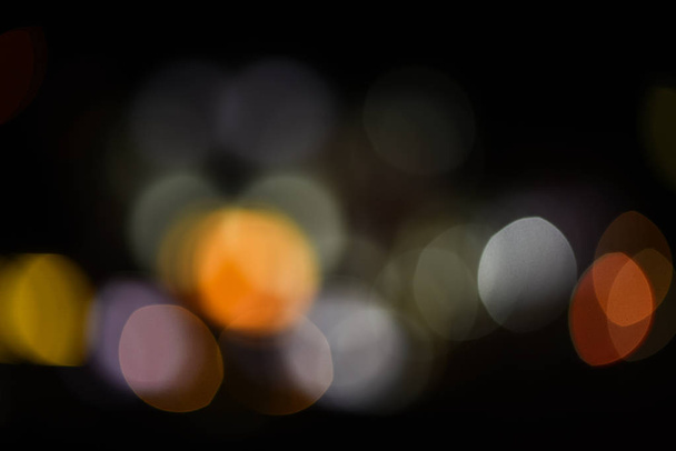 Lights of christmas garland blurred on black background. Lights of colorful garland defocused as beautiful background. Background concept. Christmas holiday decoration blurred - Zdjęcie, obraz