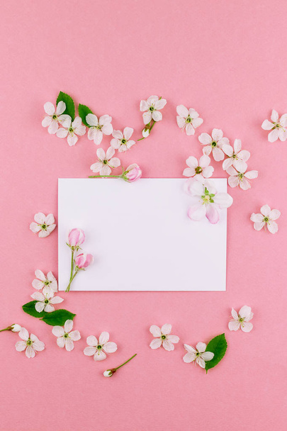 Creative flat lay concept top view of blank letter envelope and spring cherry tree flowers on millennial pink background with copy space in minimal style, template for celebration, valentine cards - Zdjęcie, obraz