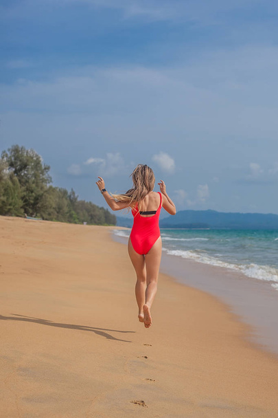 Sexy woman in red swimsuit on the beach - 写真・画像