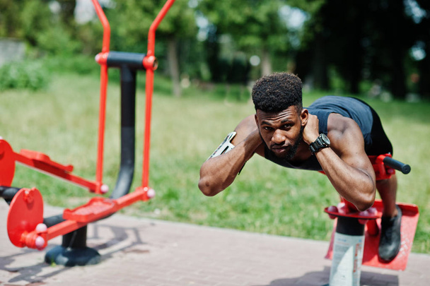 African american male athlete sport man with running sports arm case for mobile phone, doing exercises on the street workout simulators. - Foto, immagini