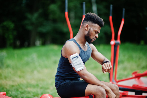 African american male athlete sport man with running sports arm case for mobile phone, doing exercises on the street workout simulators. - Фото, зображення