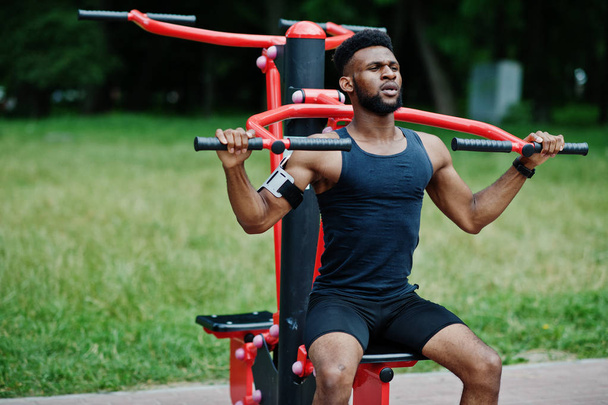 Atleta afroamericano di sesso maschile sportivo con custodia per braccio sportivo da corsa per cellulare, facendo esercizi sui simulatori di allenamento di strada
. - Foto, immagini