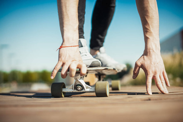 Close up of young attractive man riding longboard in the park. - Foto, Bild