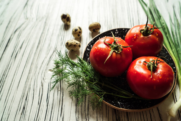 czerwone pomidory na talerzu i zieleni na biały drewniany stół - Zdjęcie, obraz