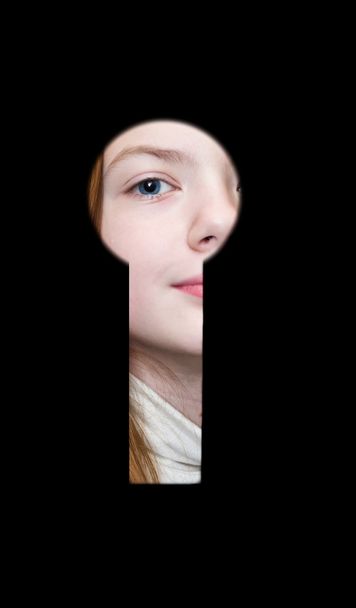 Girl a teenager spies in a keyhole. - Fotoğraf, Görsel