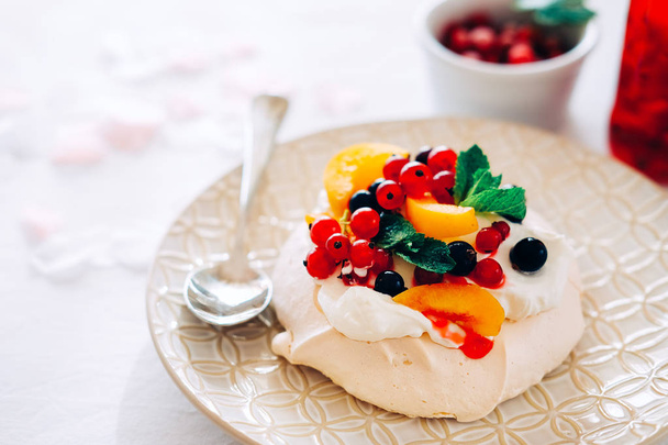 Lezzetli Pavlova tatlı beyaz beze, krema ve meyve ile porselen tabakta. Geleneksel Avustralya tatlı gıda. - Fotoğraf, Görsel