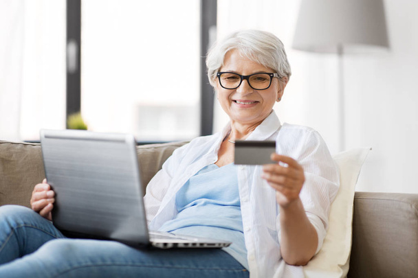 Старша жінка з ноутбуком і кредитною карткою вдома
 - Фото, зображення