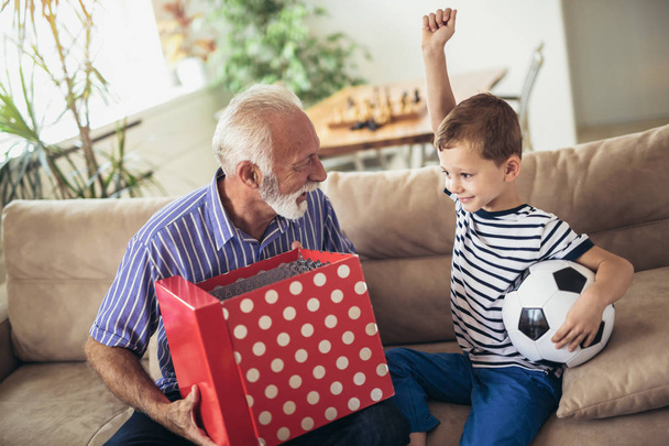 Knappe senior grootvader presenteren geschenk aan gelukkig kleinzoon - Foto, afbeelding