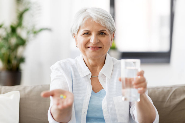 senior woman with water and medicine at home - Foto, Imagem