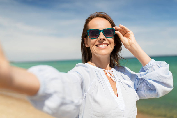 woman in sunglasses taking selfie on summer beach - Zdjęcie, obraz