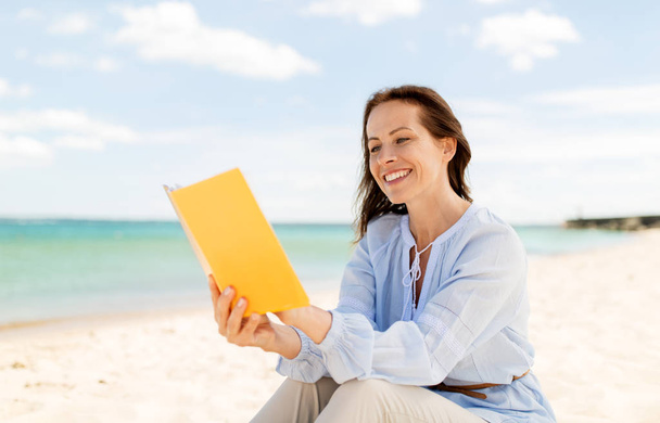 happy smiling woman reading book on summer beach - Foto, Imagen