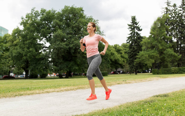 woman with earphones running at park - Photo, Image