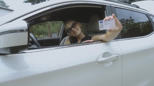 mladá šťastná žena ukazuje její nový řidičský průkaz - Záběry, video