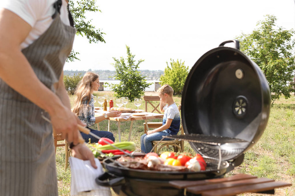 Happy family having barbecue with modern grill outdoors - Photo, image
