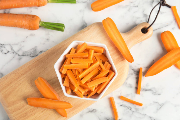 Bowl with cut ripe carrot on wooden board, top view - Φωτογραφία, εικόνα
