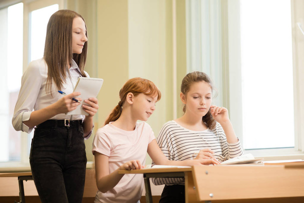 3 uczeń dziewczyny siedzą przy biurku - Zdjęcie, obraz