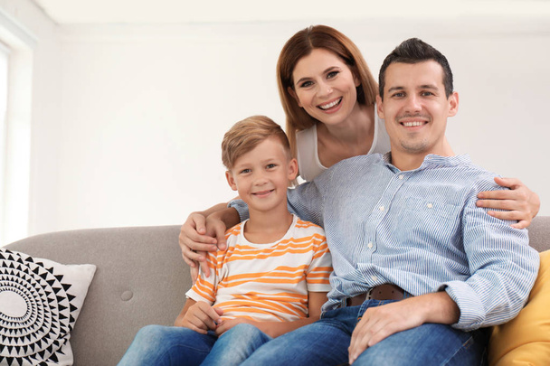 Ευτυχισμένη οικογένεια με χαριτωμένο παιδί στον καναπέ στο σπίτι - Φωτογραφία, εικόνα