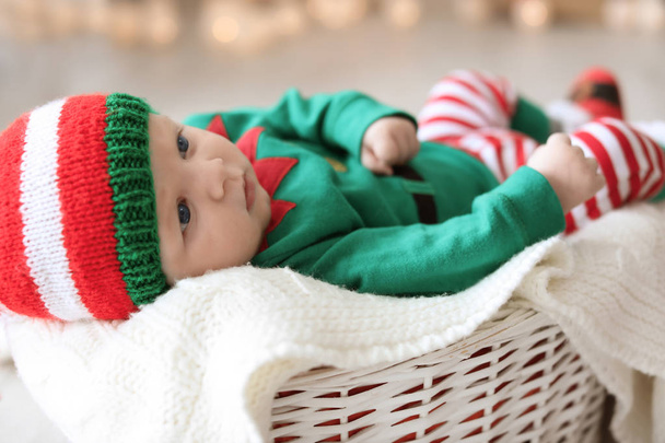 Cute baby wearing Christmas costume lying in basket at home - Foto, afbeelding