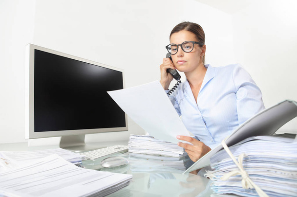 επιχειρήσεων γυναίκα που εργάζεται στο γραφείο με υπολογιστή διαβάζει ένα έγγραφα και μιλάει στο τηλέφωνο, απομονώνονται σε λευκό φόντο - Φωτογραφία, εικόνα