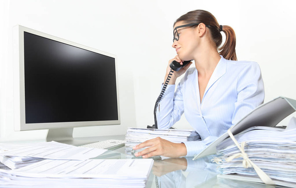 επιχειρήσεων γυναίκα που εργάζεται στο γραφείο με υπολογιστή και έγγραφα μιλάει στο τηλέφωνο και να δούμε μια κενή οθόνη, απομονώνονται σε λευκό φόντο - Φωτογραφία, εικόνα