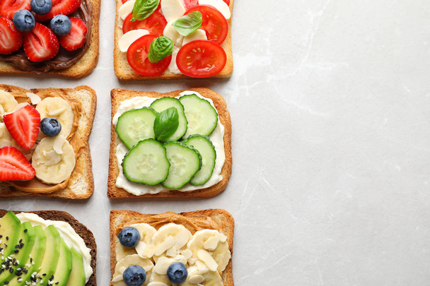 Tasty toast bread with fruits, berries and vegetables on light background - Valokuva, kuva
