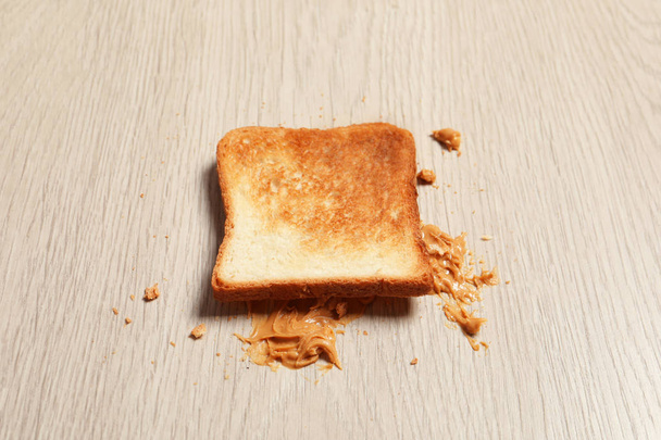 Overturned toast bread with peanut butter on floor - Photo, Image