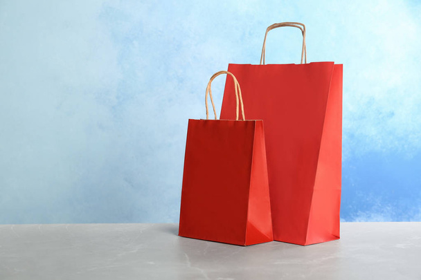 Mockup of paper shopping bags on table against color background - Foto, Imagem