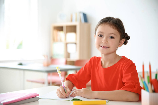 Cute little child doing assignment at desk in classroom. Elementary school - 写真・画像