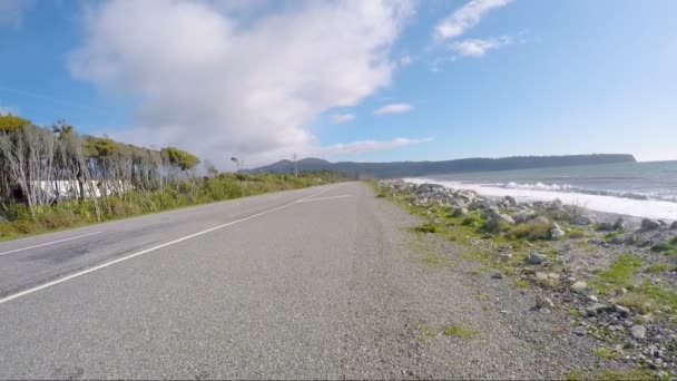 Ασιάτης άνδρας που ταξιδεύει χαλαρώνοντας στην παραλία με τα στηρίγματα δυτικά κόστος νότια της Νέας Ζηλανδίας - Πλάνα, βίντεο