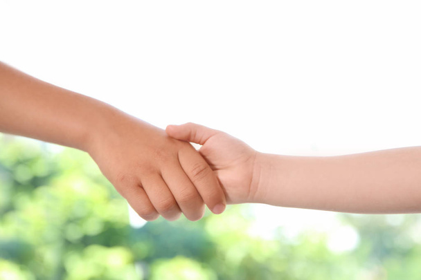Children holding hands on blurred background, closeup. Unity concept - Φωτογραφία, εικόνα