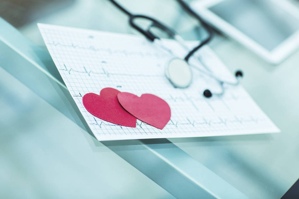  health concept: two red paper heart on the electrocardiogram, the cardiologist. - Foto, immagini