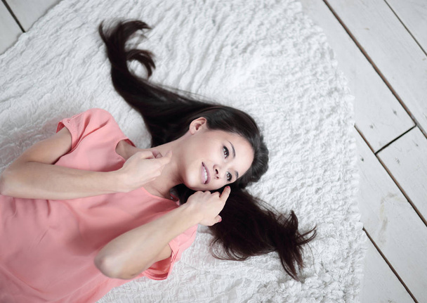 close up.thoughtful young woman lying on white carpet in living room - Foto, imagen