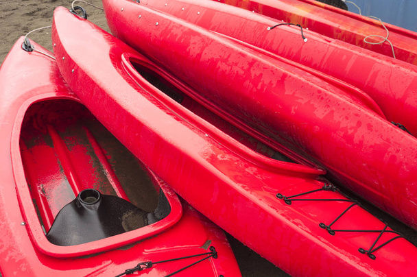 Prázdné červené plastové rekreační kajaky k pronájmu nebo pronájmu, uložené na písečné pláži po hodinách na deštivý den. Crescent Beach, Surrey, Britská Kolumbie, Kanada. - Fotografie, Obrázek
