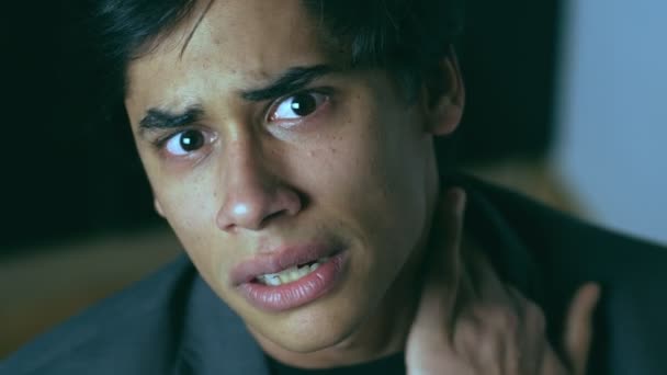 Geistesgestörter junger Mann weint und berührt seinen Hals und starrt in die Kamera - Filmmaterial, Video