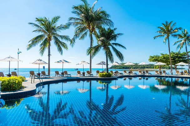 Красивий тропічний пляж і море з парасолькою і стільцем навколо басейну в готельному курорті для подорожей і відпочинку
 - Фото, зображення