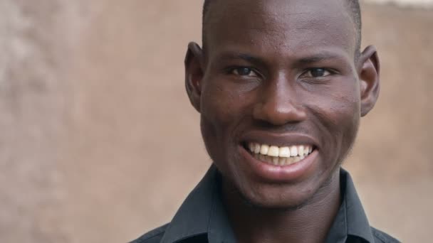 Mosolygó vonzó fekete-afrikai fiatalember látszó-on fényképezőgép-lassú mozgás - Felvétel, videó