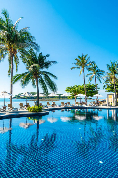 Prachtig tropisch strand en zee met parasol en stoel rond zwembad in hotel resort voor reizen en vakantie - Foto, afbeelding
