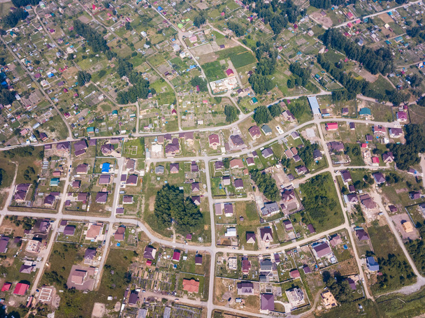 Дрон вертольота стріляв. Вид зверху на маленьке село, автомобільну дорогу, зелений ліс і велике поле в теплий, сонячний літній день
 - Фото, зображення