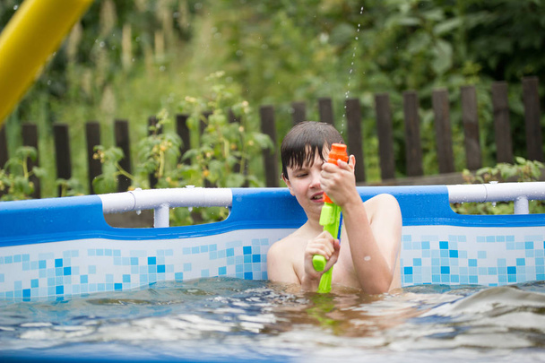 The boy shoots from a water pistol - Photo, Image