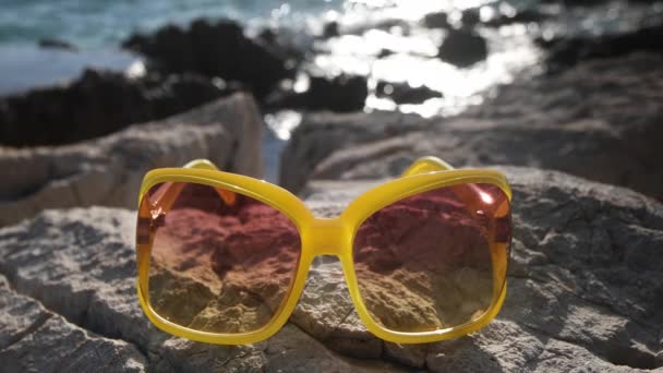 beach scene in Croatia with yellow sunglasses on rocks - Footage, Video