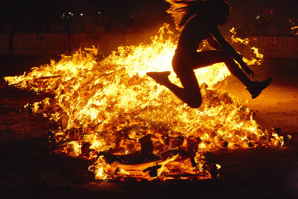 Nyári napforduló ünnepe, Spanyolország. Nő ugrik. Tűz a lángok. Vízszintes - Fotó, kép