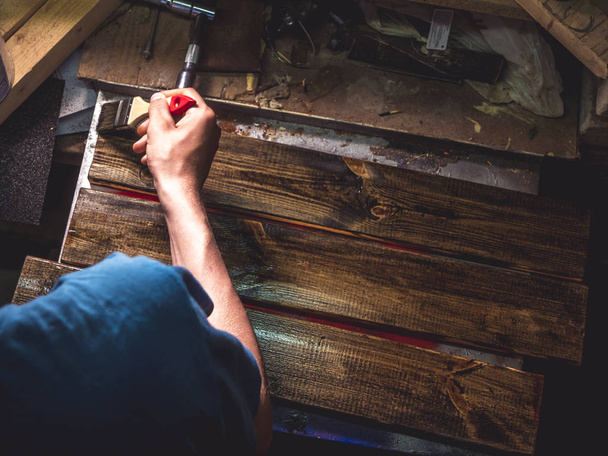 vista aérea do trabalhador pintando as barras de madeira com o pincel
 - Foto, Imagem