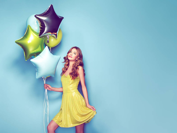 Mavi bir arka plan üzerinde renkli Balonlu güzel genç kadın. Doğum günü ve parti. Festivali yeşil elbiseli kız - Fotoğraf, Görsel