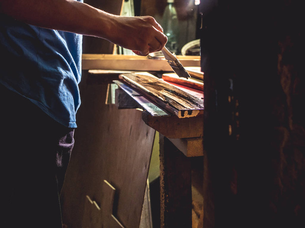 fechar a mão do pintor trabalhando com pincel com barras de madeira na sala de tecido escuro
 - Foto, Imagem
